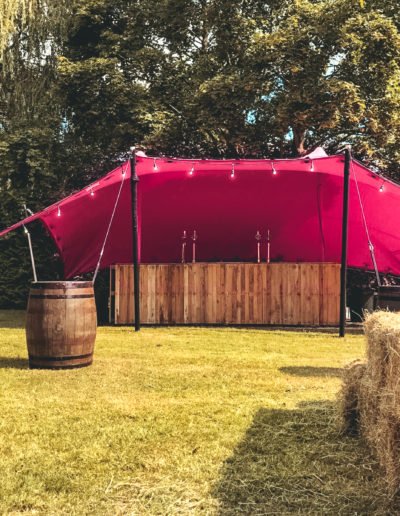 pink tent with whiskey barrels and bar