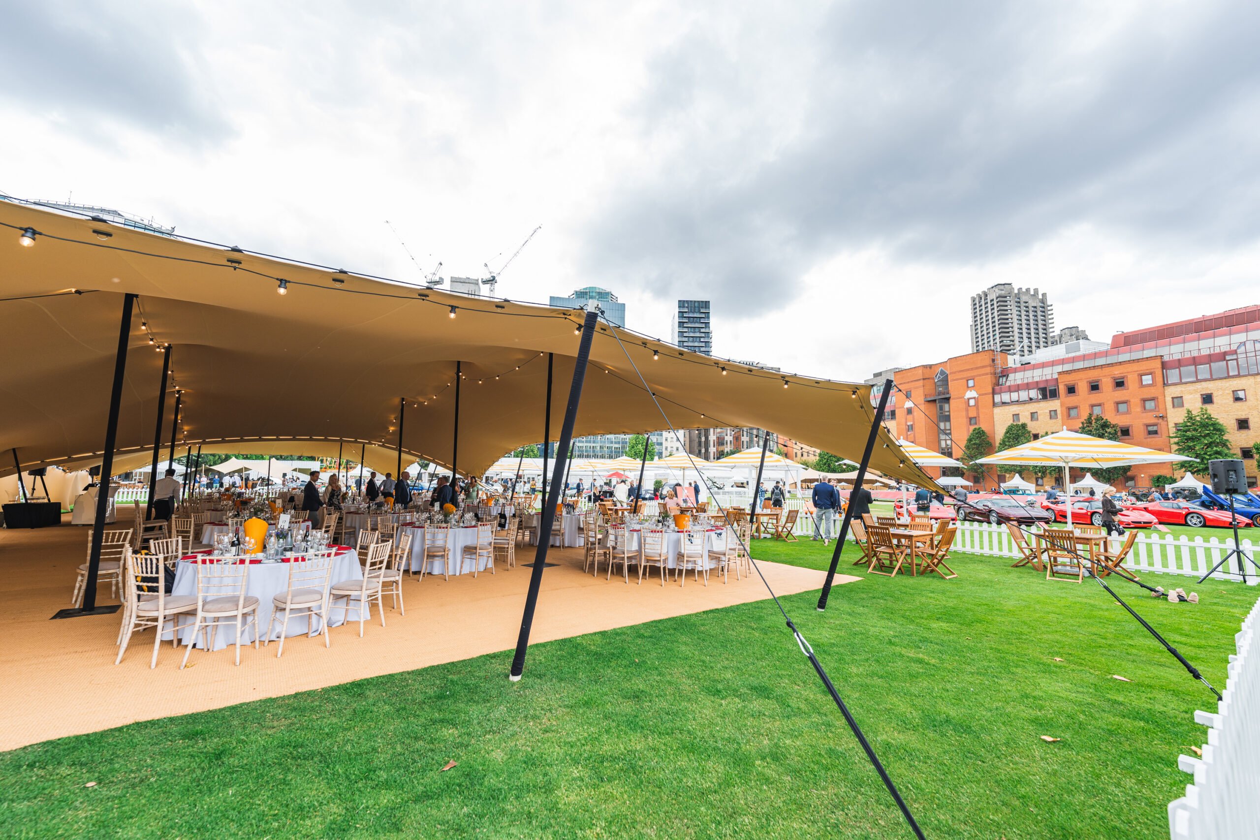 Large beige stretch tent at urban event with dining tables and city skyline backdrop