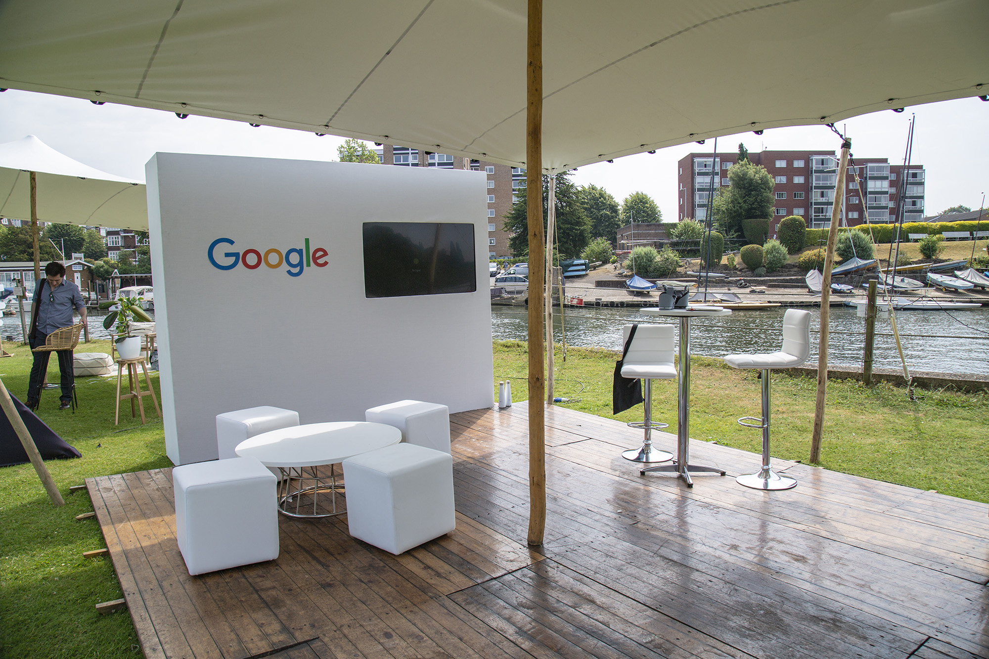 A branded exhibition stand under a white stretch tent on a riverside quay